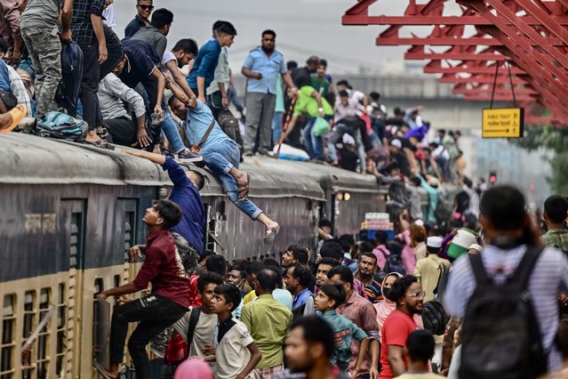 People board a train at the Tongi railway station in Tongi on the outskirts of Dhaka on June 14, 2024, as they travel back home ahead of Eid al-Adha, the feast of the sacrifice marking the end of the Hajj pilgrimage to Mecca. (Photo by Munir Uz Zaman/AFP Photo)