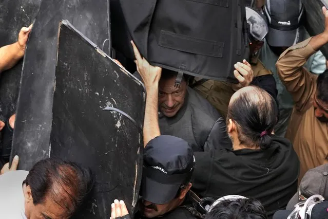 Security personnel hold bulletproof shields to secure former Prime Minister Imran Khan, center,  after appearing in a court, in Lahore, Pakistan, Tuesday, March 21, 2023. A Pakistani court on Tuesday granted Khan a weeklong bail in two cases in which he faces terrorism charges, officials said. The ruling gave the embattled ousted premier and now popular opposition leader another brief reprieve from arrest. (Photo by K.M. Chaudary/AP Photo)