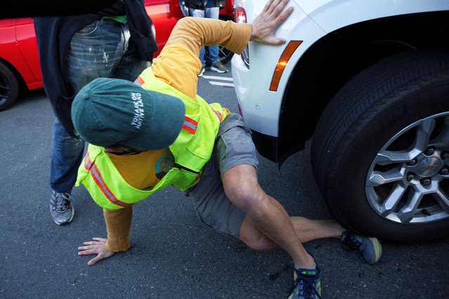 A protester's foot is caught under a car's wheel during a protest against the arrival of federal agents at the Coast Guard base in Alameda, California, U.S, October 23, 2025. (Photo by Manuel Orbegozo/Reuters)