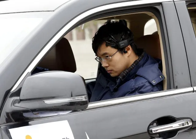 Researcher Zhang Zhao wearing a brain signal-reading equipment prepares to move a car with his brain wave, during a demonstration at Nankai University in Tianjin, China, November 17, 2015. Researchers from ISI lab at the university claim the car can move straight forward, backward, come to a stop, be locked and unlocked with their brain-controlled vehicle system. (Photo by Kim Kyung-Hoon/Reuters)