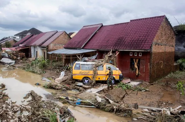 The wreckage of a van is seen near a damaged house at a neighborhood affected by a flood in Medan, North Sumatra, Indonesia, Friday, December 4, 2020. Torrential rains in the country's third largest city swelled rivers and flooded thousands of homes leaving a number of people killed and missing. (Photo by Binsar Bakkara/AP Photo)