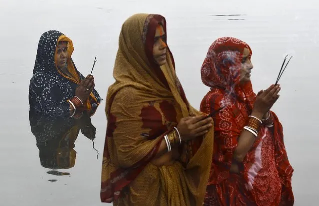 Hindu women worship the sun god Surya while standing in the waters of a pond during the Hindu religious festival of Chatt Puja in Kolkata, India, November 18, 2015. (Photo by Rupak De Chowdhuri/Reuters)