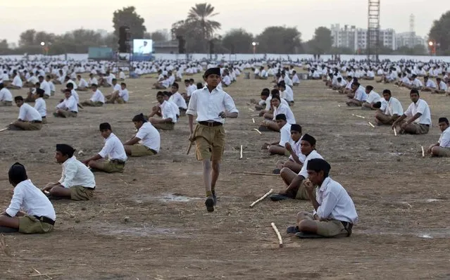 A youth volunteer of the Hindu nationalist organisation Rashtriya Swayamsevak Sangh (RSS) runs as others sit on the ground during a drill on the last day of their three-day workers' meeting in the western Indian city of Ahmedabad January 4, 2015. (Photo by Amit Dave/Reuters)