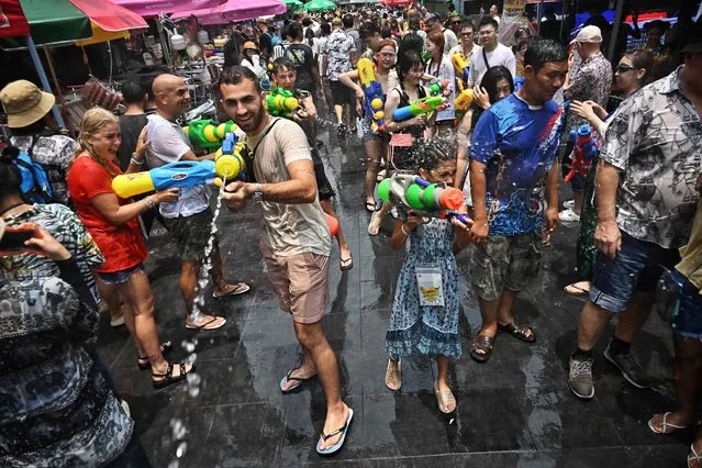 People take part in mass water fights during the first day of Songkran, or Thai New Year, on Khao San Road in Bangkok on April 13, 2023. (Photo by Lillian Suwanrumpha/AFP Photo)