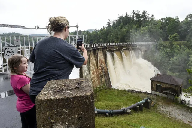 Amanda Harrod of Nebo, North Carolina with her daughter, Addisyn takes photos of the water flowing from the Lake Tahoma Dam on Wednesday, May 30, 2018, in Marion, N.C. Continuous rain over the last several days has raised the water level of the dam and forced evacuations of local residents. (Photo by Kathy Kmonicek/AP Photo)