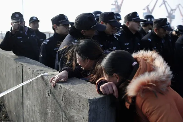 Relatives of a missing person cry next to police officers on the bank of the Yangtze River, near Jingjiang, Jiangsu province January 17, 2015. (Photo by Aly Song/Reuters)
