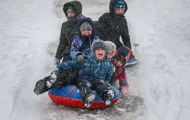Children ride the ice slide after school lessons in a park during a snowfall in Moscow, Russia, 21 January 2021. The temperature dropped to minus 11 degrees Celsius. (Photo by Yuri Kochetkov/EPA/EFE)