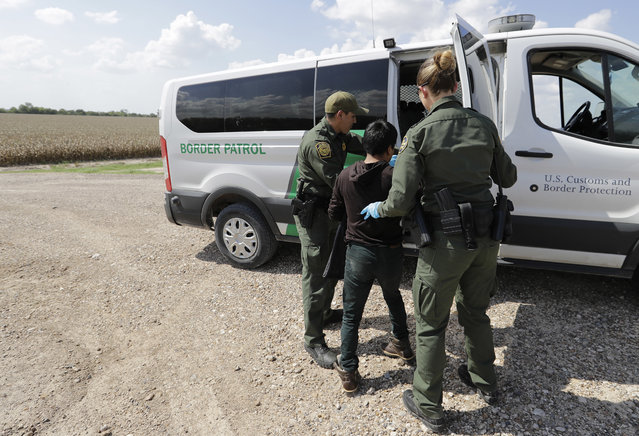 U.S. Border Patrol agents load a migrant from Guatemala into a van after he was caught trying to enter the United States illegally, Monday, June 25, 2018, in Hidalgo, Texas. (Photo by David J. Phillip/AP Photo)