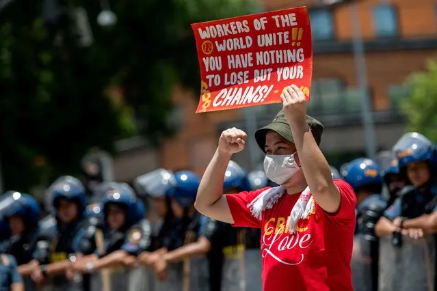 A Filipino labor activist holds a placard as he raises his fist, during a Labor Day protest near the US Embassy, in Manila, Philippines on May 1, 2023. (Photo by Lisa Marie David/Reuters)