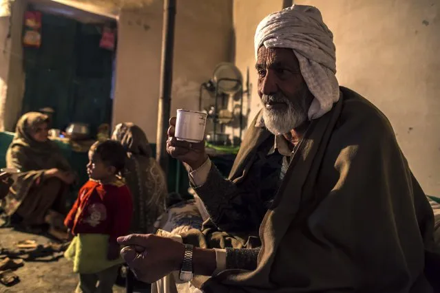 A man holds a cup of tea while he sits with his family at their house on Margalla Hills in Islamabad January 22, 2015. (Photo by Zohra Bensemra/Reuters)