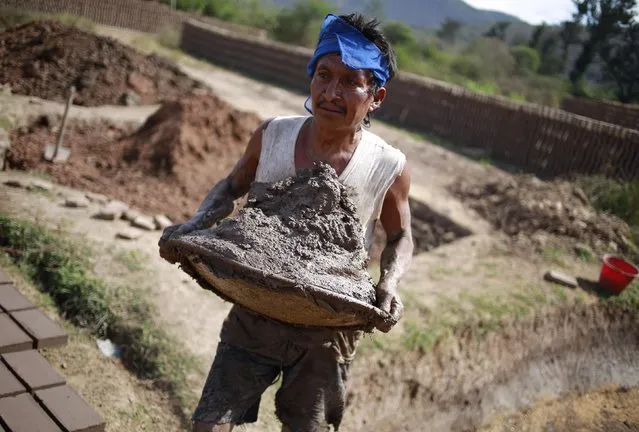 A worker carries mud used to make bricks at a brick factory in Tixtla, on the outskirts of Chilpancingo, in the Guerrero state, January 26, 2015. (Photo by Jorge Dan Lopez/Reuters)