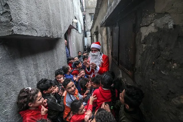 A Palestinian man dressed in a Santa Claus costume spreads happiness among the camp children amid the ongoing coronavirus COVID-19 pandemi​c, in Al Shatea refugee camp in Gaza City, 16 December 2020. (Photo by Mohammed Saber/EPA/EFE)