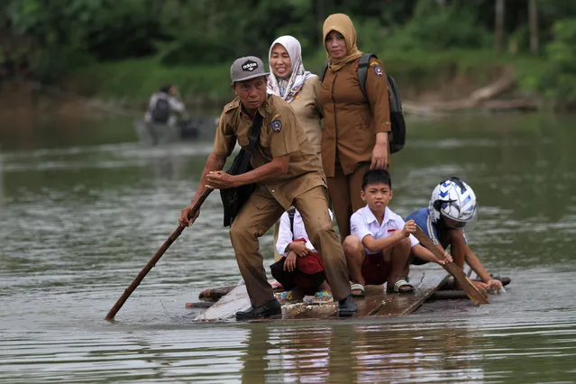 A group of teachers and their student use makeshift raft as they cross the street during flood that hit Ranomeeto Barat village in Konawe Selatan, Sulawesi island, Indonesia, July 10, 2018. (Photo by Jojon/Reuters/Antara Foto)