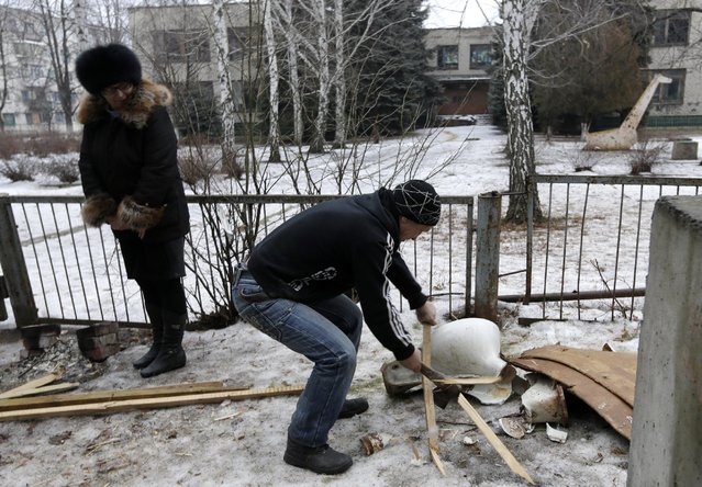 A man chops wood to light a fire outside of his home in the town Svitlodarsk, Ukraine, Friday, January 30, 2015. Shelling of the town Thursday, which destroyed the local hospital, has damaged basic infrastructure, cutting off electricity, water and household gas supplies. Fighting is raging nearby between government and Russian-backed separatists for control of the railway hub in the town of Debaltseve. (Photo by Petr David Josek/AP Photo)