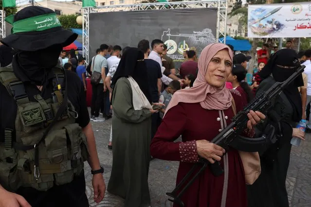 A Palestinian poses for a souvenir picture with a machine gun during an exhibition by the Ezzedine al-Qassam Brigades, the military wing of the Palestinian Hamas movement, in Gaza City on June 30, 2023. (Photo by Mohammed Abed/AFP Photo)