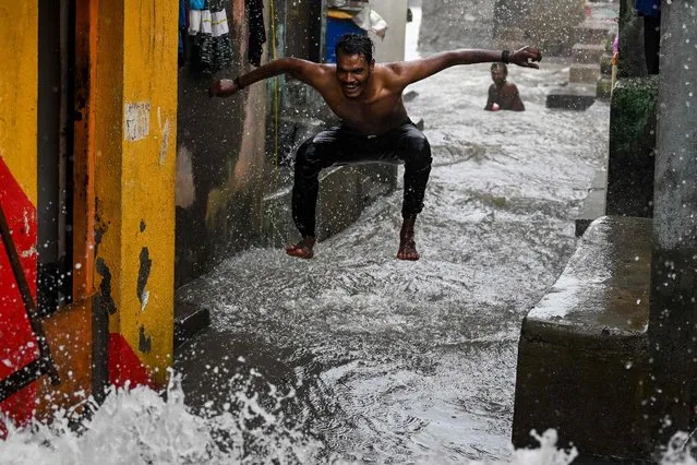 A man enjoys rain showers during high tides near the sea front in Mumbai on July 6, 2023. (Photo by Punit Paranjpe/AFP Photo)