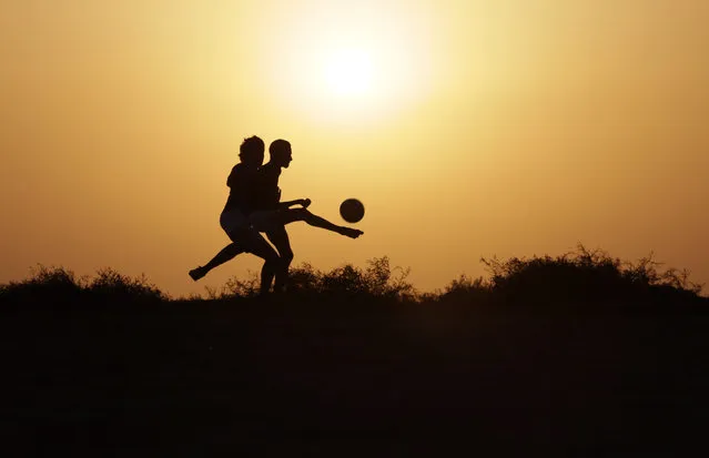 In this picture taken Thursday, November 12, 2015, Bahraini youths play soccer on a village field as the sun sets in Malkiya, Bahrain. (Photo by Hasan Jamali/AP Photo)