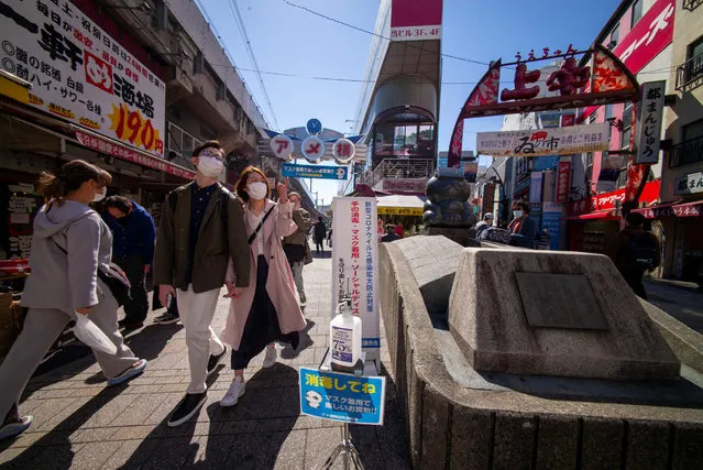 An alcohol bottle (bottom) is installed on a street of Ueno shopping district to encourage shoppers to disinfect their hands in Tokyo on March 14, 2021 to prevent infection with the COVID-19 coronavirus. (Photo by Kazuhiro Nogi/AFP Photo)