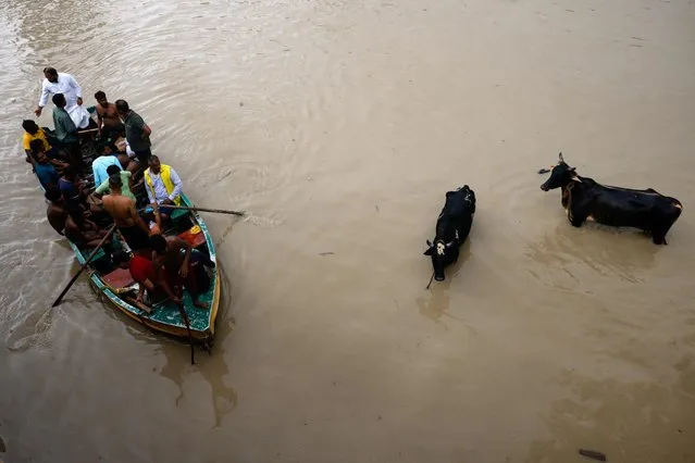 A boat carrying people moves over a flooded road, after a rise in the water level of the river Yamuna due to heavy monsoon rains, in New Delhi, India on July 14, 2023. (Photo by Adnan Abidi/Reuters)
