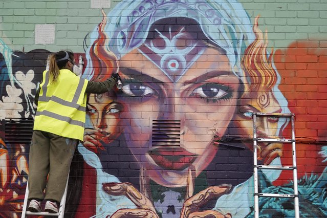 British artist Vicky Lim, a member of the Wom Collective, a female street art collective, works on their new piece of street art in Brixton, south London, on March 7, 2021 to celebrate International Women's Day. (Photo by Niklas Halle'n/AFP Photo)