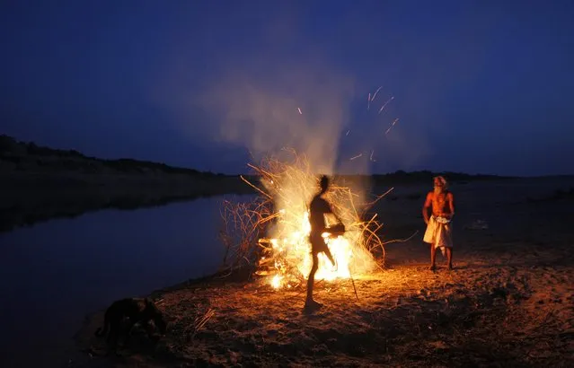 In this photo taken Monday, April 28, 2014, flames rise from the cremation pyre of an elderly woman on the banks of the Chambal River near Bhopepura village, in the northern Indian state of Uttar Pradesh. (Photo by Altaf Qadri/AP Photo)