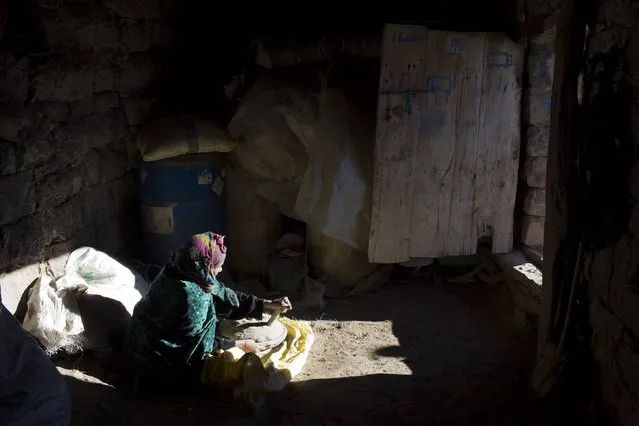 A woman prepares wheat bread in her doorway in Ait Sghir village in the High Atlas region of Morocco February 14, 2015. (Photo by Youssef Boudlal/Reuters)