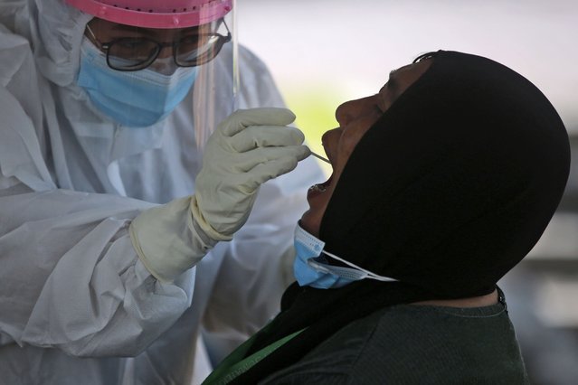 A medical worker collects a nasal swab sample during a mass screening for coronavirus at North Sumatra University Hospital in Medan, North Sumatra, Indonesia, Monday, June 28, 2021. The world's fourth most populous country has seen COVID-19 infections surge in recent weeks, putting pressure on hospitals and has added urgency to the government's plan to inoculate 1 million people each day by next month. (Photo by Binsar Bakkara/AP Photo)