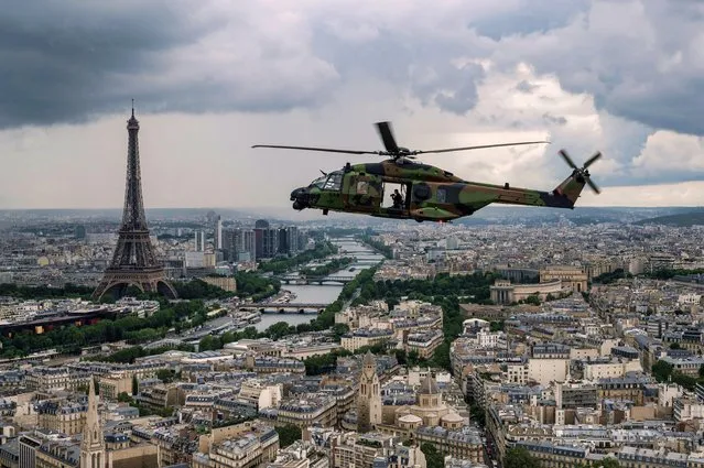 An NH90 “Caiman” helicopter flies over the Eiffel Tower and the Seine river during a practice session prior to July 14's Bastille Day Parade in Paris on July 12, 2021. (Photo by Bertrand Guay/AFP Photo)