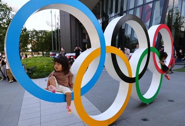 A child sits on the Olympic Rings outside The National Stadium, the main venue of the Tokyo 2020 Olympic Games, July 20, 2021. (Photo by Kim Kyung-Hoon/Reuters)