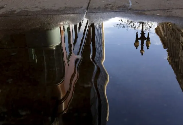 A building is reflected in a rain puddle on Market Street in San Francisco California April 7, 2015. (Photo by Robert Galbraith/Reuters)