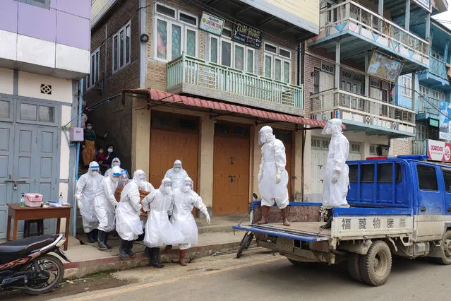 This handout photo from local media group Tedim Post taken and released on June 29, 2021, shows health workers carrying a coffin bearing the remains of a Covid-19 coronavirus victim who died at home in Tedim, western Chin state, as more than two million people in Myanmar were placed under new stay-at-home measures July 2 as infections in the coup-wracked country surge. (Photo by Tedim Post/Handout via AFP Photo)