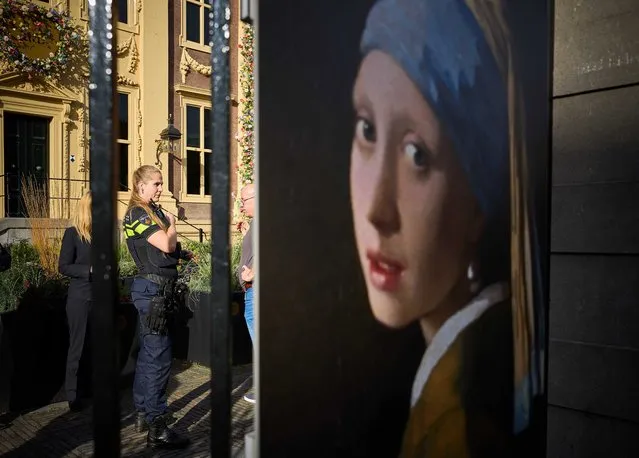 A police officer (L) stands outside the Mauritshuis museum, where three people were arrested for attempting to smudge Vermeer's painting “Girl with a Pearl Earring”, currently exhibited there, in The Hague, Netherlands, 27 October 2022. They were wearing shirts from the Just Stop Oil campaign group, whose members are responsible for recent acts of vandalism – such as throwing soup at paintings, sports cars and luxury shop windows across Europe – in an attempt to raise awareness about their protest against fossil fuels. (Photo by Phil Nijhuis/EPA/EFE)