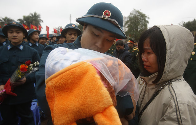 New recruit Nguyen Duc Trung (C) kisses his one month old son Quoc Dung as his wife, Luong Thuy Quynh, cries during a military recruitment ceremony at the Quan Ngua stadium in Hanoi, Vietnam, February 23, 2016. (Photo by Reuters/Kham)