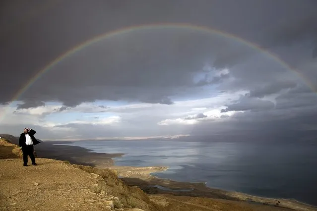 An Ultra Orthodox Jewish man looks on a rainbow over the Dead Sea in Israel, 14 December 2016, during a stormy weather which is forecasted across the country. (Photo by Abir Sultan/EPA)