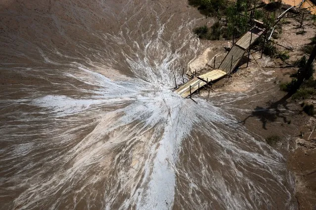 This view from a police helicopter shows a “tolba”, a sluice-like apparatus layered with pieces of carpet to capture gold deposits from water sediment, during a Wednesday, February 24, 2016 government raid to destroy illegal gold mining operations in the deforested area known as La Pampa in Peru's Madre de Dios region. This week's raid was one of the biggest of more than 60 operations the government has launched since 2014 when wildcat mining was outlawed. (Photo by Rodrigo Abd/AP Photo)