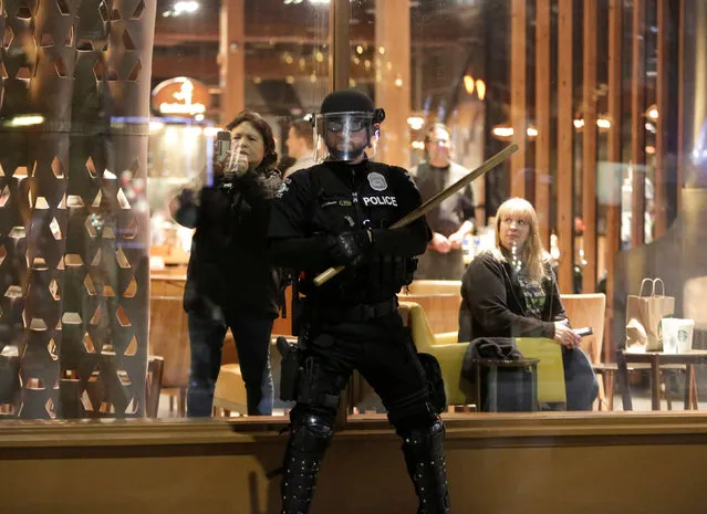 A Seattle policeman stands in front of the Starbucks Reserve Roastery and Tasting Room as people march past in protest to U.S. President Donald Trump's inauguration in Seattle, Washington, U.S. January 20, 2017. (Photo by Jason Redmond/Reuters)