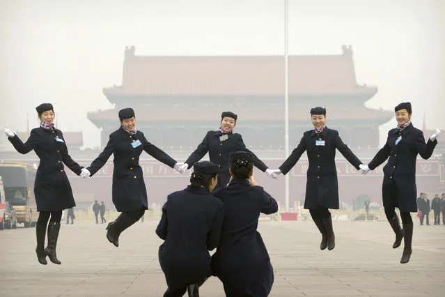 Hostesses, who facilitated the transportation of delegates arriving by bus, pose for photos on Tiananmen Square near the Great Hall of the People in Beijing during a meeting ahead of Saturday's opening session of China's National People's Congress (NPC), Friday, March 4, 2016. The political conclave comes as China's leaders are being tested by new challenges including an economy that has slowed to a 25-year low, global uncertainty over the country's tumultuous stock markets and currency movements, and tensions over the South China Sea. (Photo by Mark Schiefelbein/AP Photo)