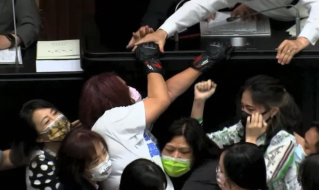 In this image taken from video by Taiwan's EBC, opposition Nationalist party lawmaker Chen Yu-jen, in white shirt, is grabbed by ruling Democratic Progressive Party lawmakers as she tries to climb onto the podium during a parliament session in Taipei, Taiwan, Tuesday, September 28, 2021. Taiwan's legislature on Tuesday descended into a rowdy brawl on Tuesday, after opposition lawmakers interrupted an important policy address and rushed the podium. (Photo by EBC via AP Photo)