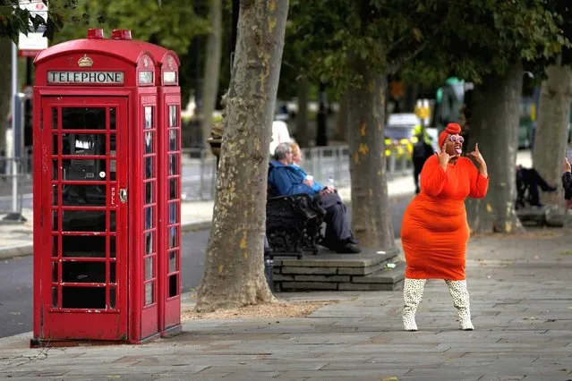 A model poses in front of phone boxes for a photographer in London, Friday, October 1, 2021. (Photo by Frank Augstein/AP Photo)