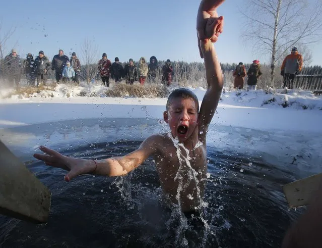 A boy reacts in the ice cold water after plunging into it during Orthodox Epiphany celebrations at a lake in the village of Zadomlya, Belarus, Sunday, January 19, 2014.  (Photo by Sergei Grits/AP Photo)