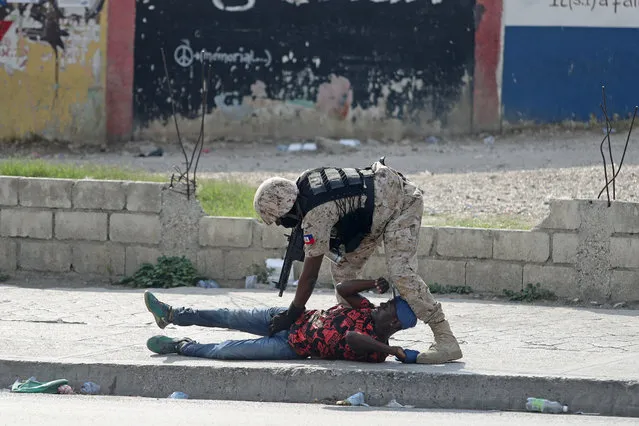 A police officer inspects a man at the airport area during anti-government protests in Port-au-Prince, February 15, 2019. (Photo by Ivan Alvarado/Reuters)