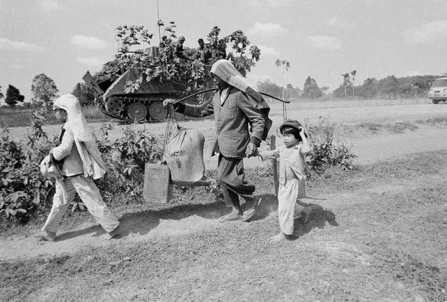 Refugees pass South Vietnamese armored vehicle as they flee from the embattled town of Tri Tam which fell to North Vietnamese troops in Vietnam, Wednesday, March 14, 1975. The town is 40 miles northwest of Saigon. (Photo by AP Photo/Phuoc)