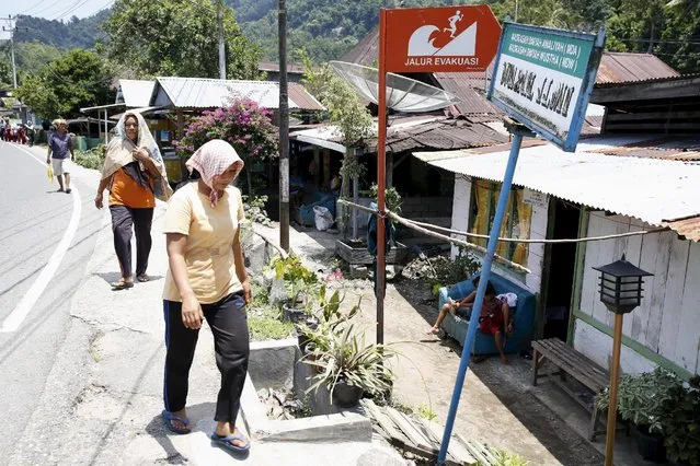 Women walk near a sign on their way home marking a tsunami evacuation route a day after a 7.8 magnitude quake struck far out at sea near Padang, West Sumatra province, Indonesia March 3, 2016. (Photo by Darren Whiteside/Reuters)