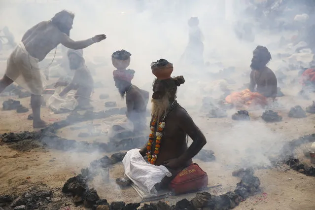 Sadhus, or Hindu holy men, perform a ritual by burning dried cow dung cakes in earthen pots at Sangam, confluence of rivers Ganges, Yamuna, and mythical Saraswati, on “Basant Panchami” festival at the annual traditional fair of Magh Mela in Allahabad, India, Wednesday, February 1, 2017. Basant Panchami is celebrated by worshipping Hindu Goddess of knowledge and wisdom, Saraswati and marks the advent of spring. Hundreds of thousands of devout Hindus bathe at the confluence during the astronomically auspicious period of over 45 days celebrated as “Magh Mela”. (Photo by Rajesh Kumar Singh/AP Photo)