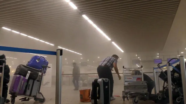 In this photo provided by Ralph Usbeck an unidentified traveller gets to his feet in a smoke filled terminal at Brussels Airport, in Brussels after explosions Tuesday, March 22, 2016. Authorities locked down the Belgian capital on Tuesday after explosions rocked the Brussels airport and subway system, killing  a number of people and injuring many more. Belgium raised its terror alert to its highest level, diverting arriving planes and trains and ordering people to stay where they were. Airports across Europe tightened security. (Photo by Ralph Usbeck via AP Photo)