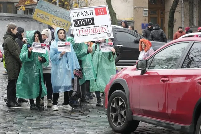 Demonstrators hold posters reading “Say No to genocide” as they try to block a street during an anti-vaccination protest in Kyiv, Ukraine, Wednesday, November 3, 2021. In a bid to stem contagion, Ukrainian authorities have required teachers, government employees and other workers to get fully vaccinated by Nov. 8 or face having their salary payments suspended. In addition, proof of vaccination or a negative test is now required to board planes, trains and long-distance buses. (Photo by Efrem Lukatsky/AP Photo)