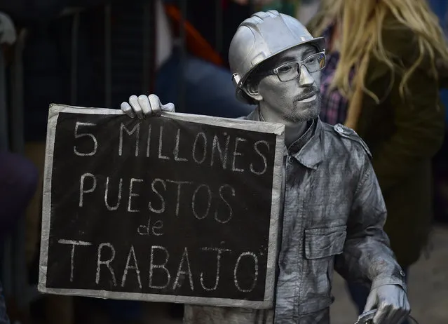 A man doused in silver body paint holds a sign with a message that reads in Spanish: “Five thousand jobs”, in reference to the informal job market, attends the kick-off campaign rally of presidential candidate Alberto Fernandez and his running mate, former President Cristina Fernandez, in Buenos Aires, Argentina, Saturday, May 25, 2019. (Photo by Gustavo Garello/AP Photo)