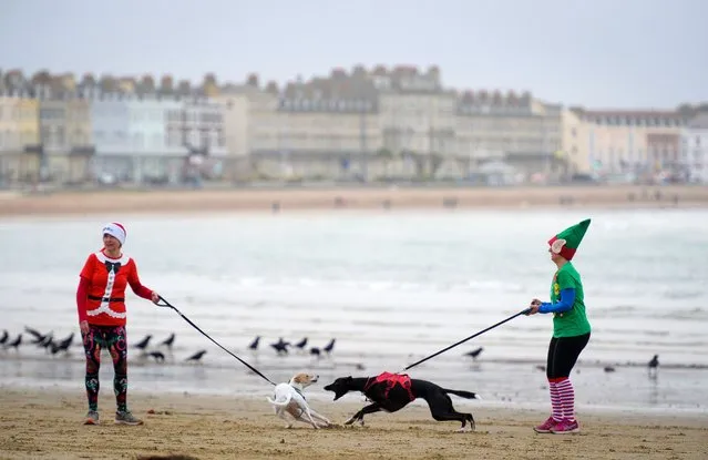 Participants in the Chase the Pudding race are seen on December 19, 2021 in Weymouth, England. The Chase the Pudding race is approximately 5km with Mr & Mrs Pudding being chased along the beach by hundreds of Santa's. The Chase the Elf race for under 14s is 2km. The event raises money for the Will Mackaness Trust. (Photo by Finnbarr Webster/Getty Images)