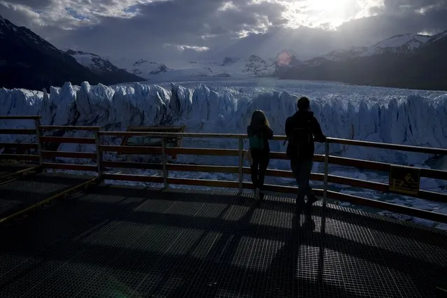 Tourists watch the Perito Moreno Glacier at Los Glaciares National Park, near El Calafate, Argentina, Monday, November 1, 2021. World leaders are gathered in Scotland at a United Nations climate summit, known as COP26, to push nations to ratchet up their efforts to curb climate change. Experts say the amount of energy unleashed by planetary warming could melt much of the planet's ice, raise global sea levels and increase extreme weather events. (Photo by Natacha Pisarenko/AP Photo)