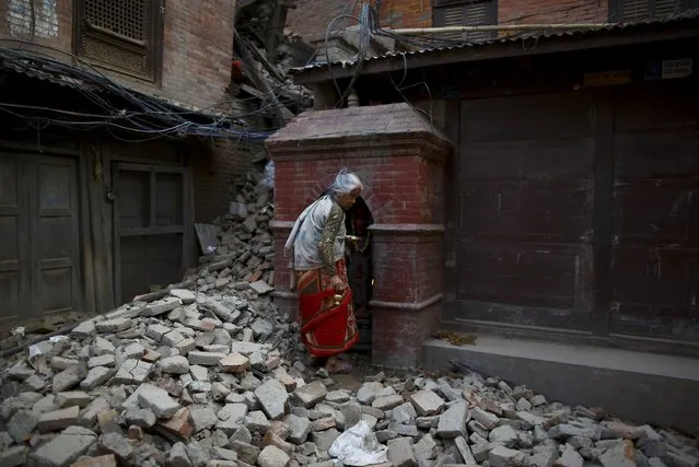 A woman walks on top of debris of a collapsed house as she returns after offering daily prayers at a temple, a month after the April 25 earthquake in Kathmandu, Nepal May 25, 2015. (Photo by Navesh Chitrakar/Reuters)